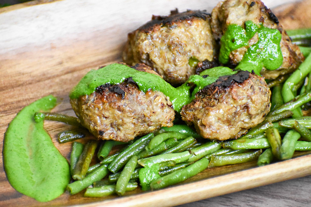 Low carb cheesy meatballs on green beans and cilantro sauce on top