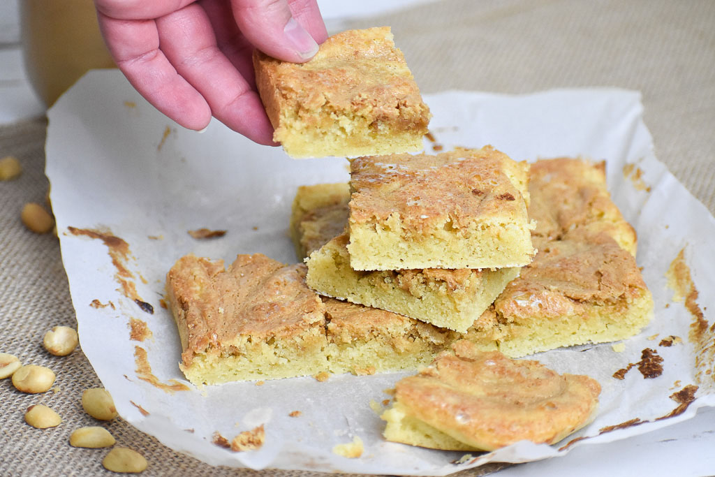 Low carb peanut butter swirl blondies with peanuts on a brown cloth 