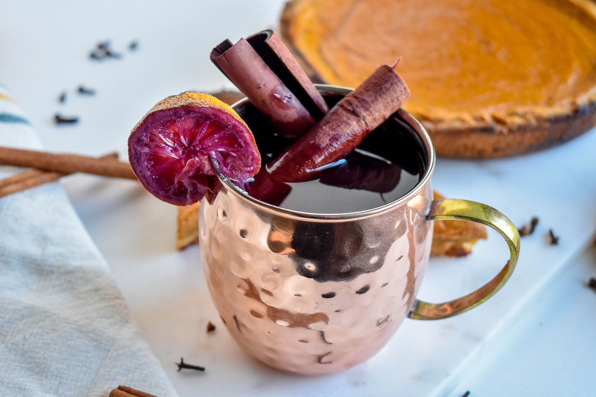 Glühwein in a mosque mule cup with pumpkin pie in the background or marble