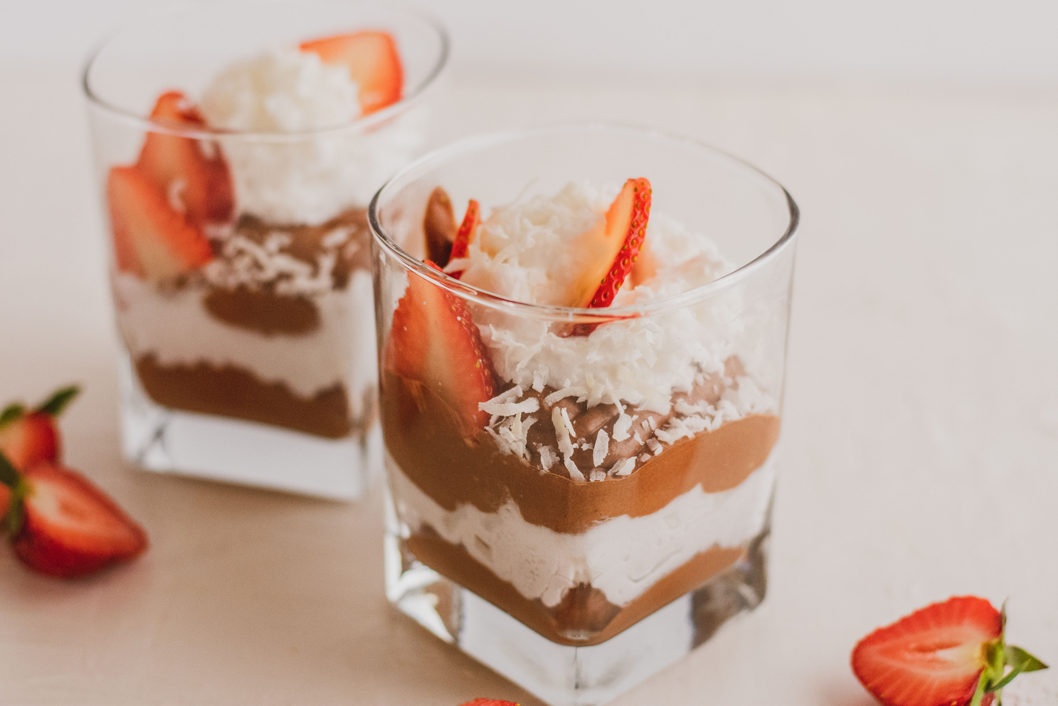 low carb Chocolate pudding with whipped cream topped with strawberries on a white surface