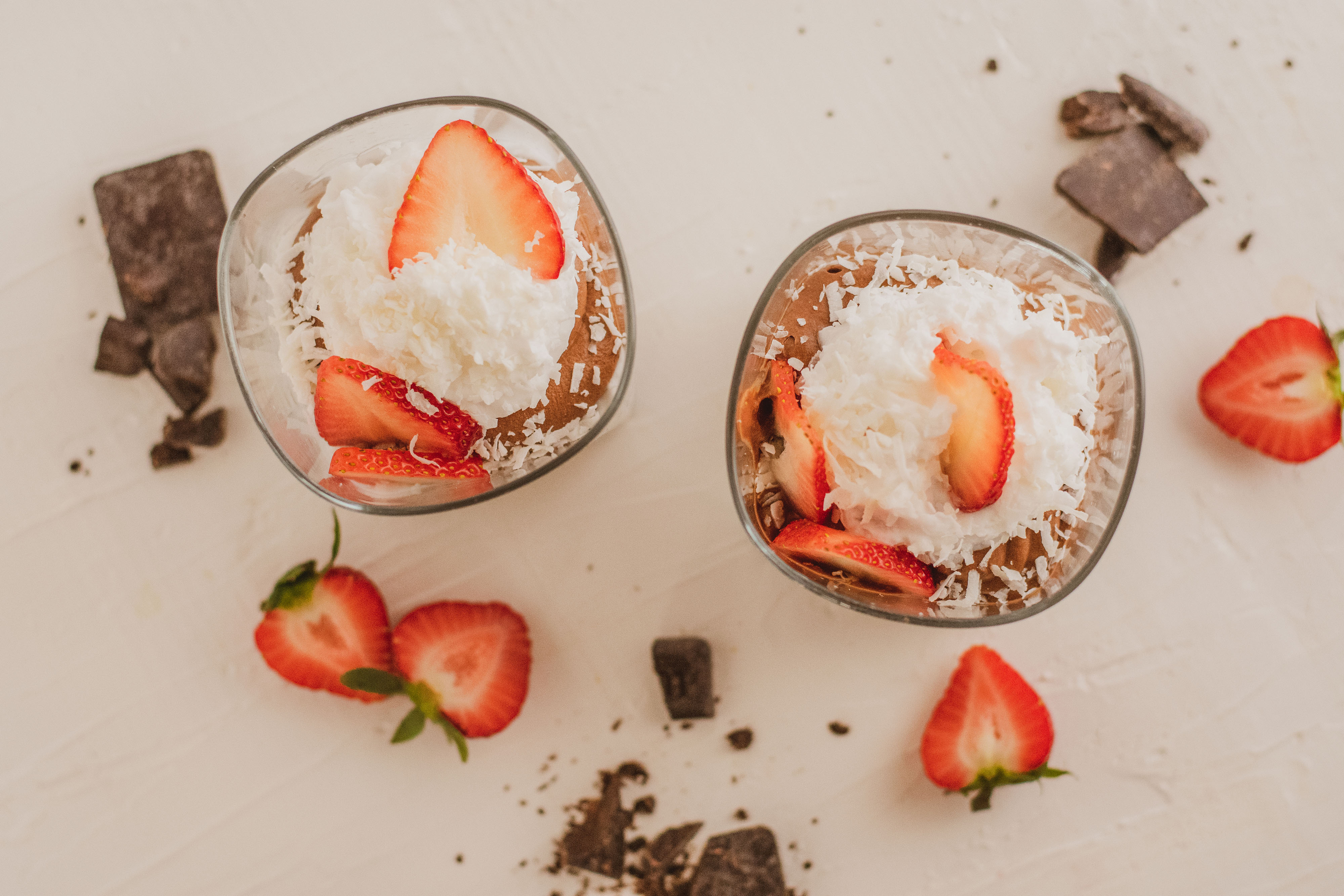 low carb Chocolate pudding with whipped cream topped with strawberries  on a white surface