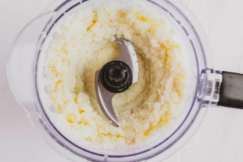 Mashed cauliflower blended in a blender on a white surface. 