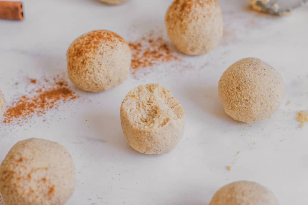 Keto Pumpkin Spice Fat Bombs rolled into balls with cinnamon on top on a white surface.