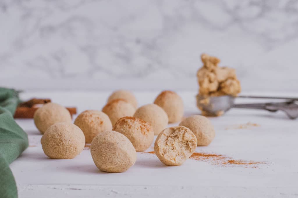Keto Pumpkin Spice Fat Bombs rolled into balls with cinnamon on top on a white surface.
