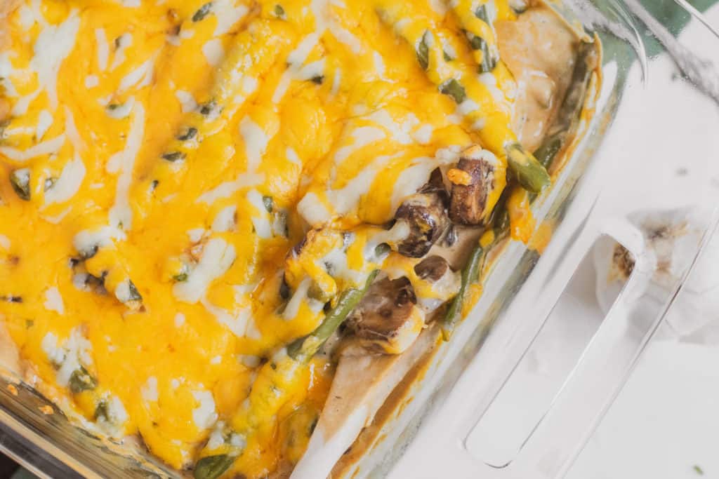 Low carb green bean casserole with melted cheese on top in a casserole dish.