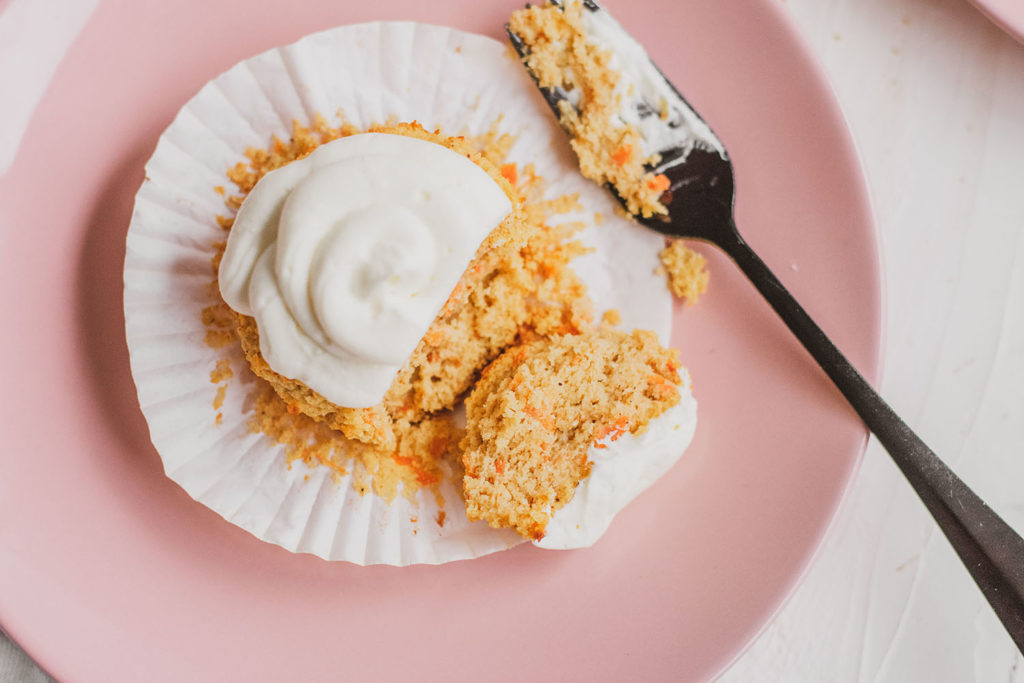 Keto carrot cake muffins on a pink plate with a black fork taking a bite.