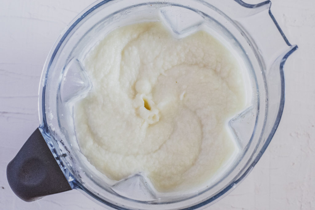 Cauliflower mash in a Vitamix blender on a white surface. 