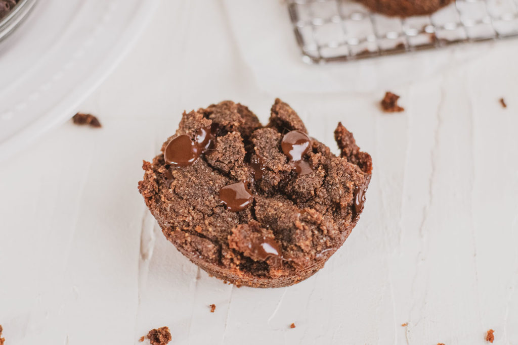 A delicious moist and fudgy Chocolate Banana Muffin keto recipe on a white surface.