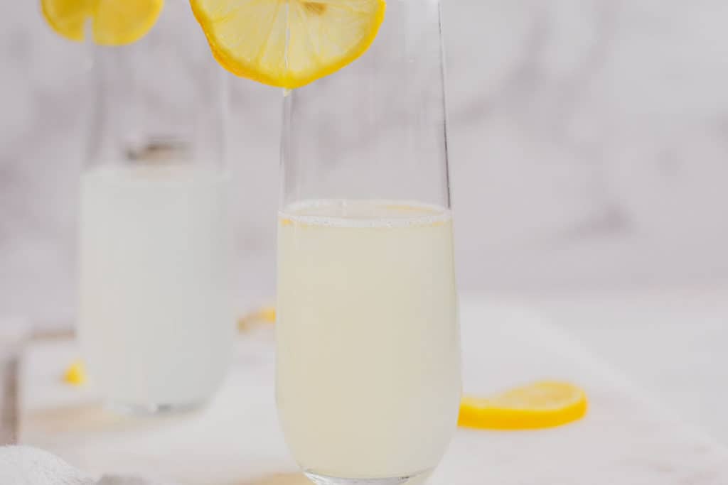 Keto Lemon Drop Cocktail in a clear glass on a white surface with lemon slices.