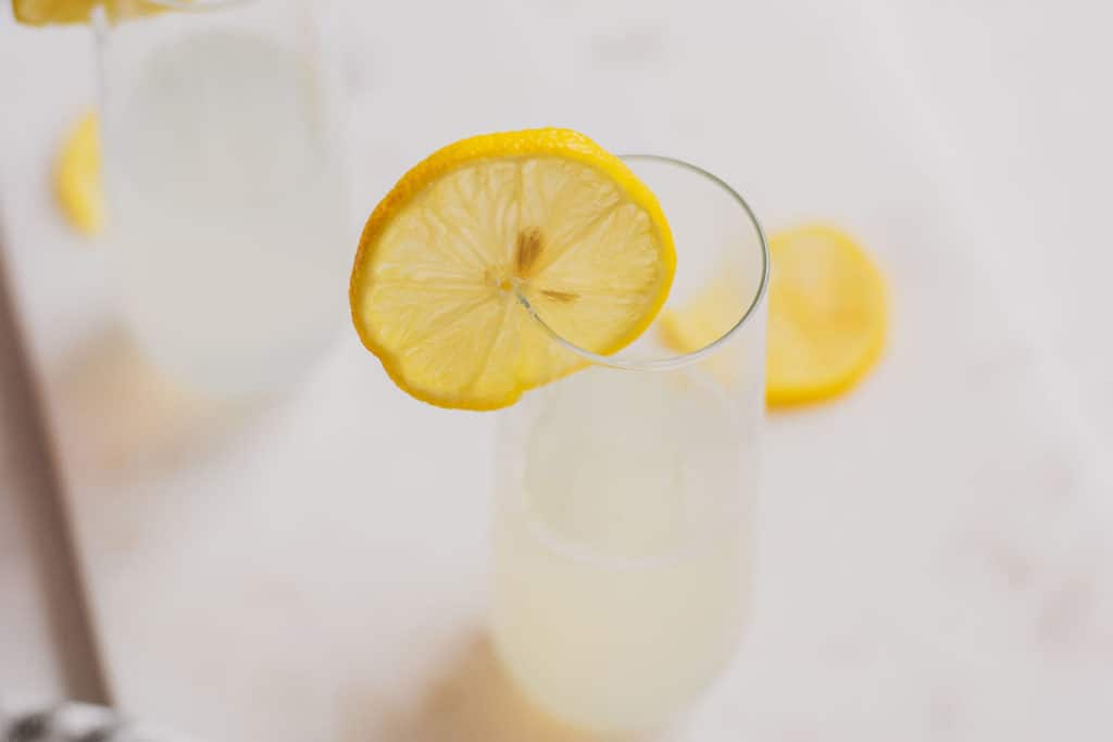 Keto Lemon Drop Cocktail in a clear glass on a white surface with lemon slices.