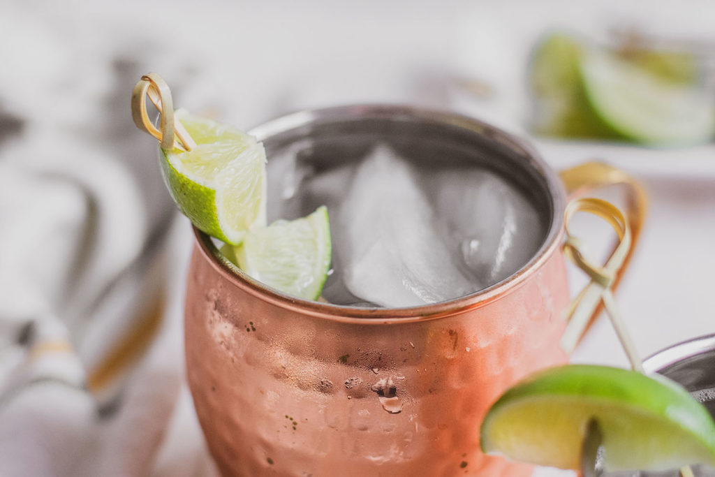 Keto Moscow Mule in brass mugs with a lime slice on the rim on a white surface.