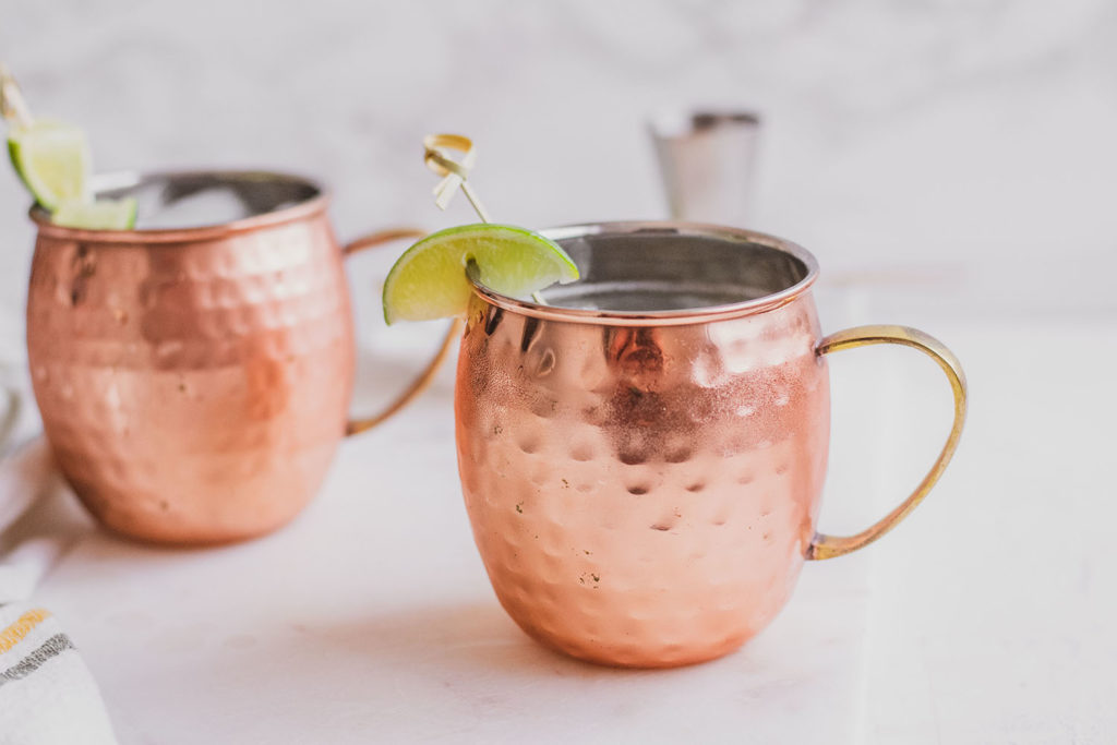 Keto Moscow Mule in brass mugs with a lime slice on the rim on a white surface.