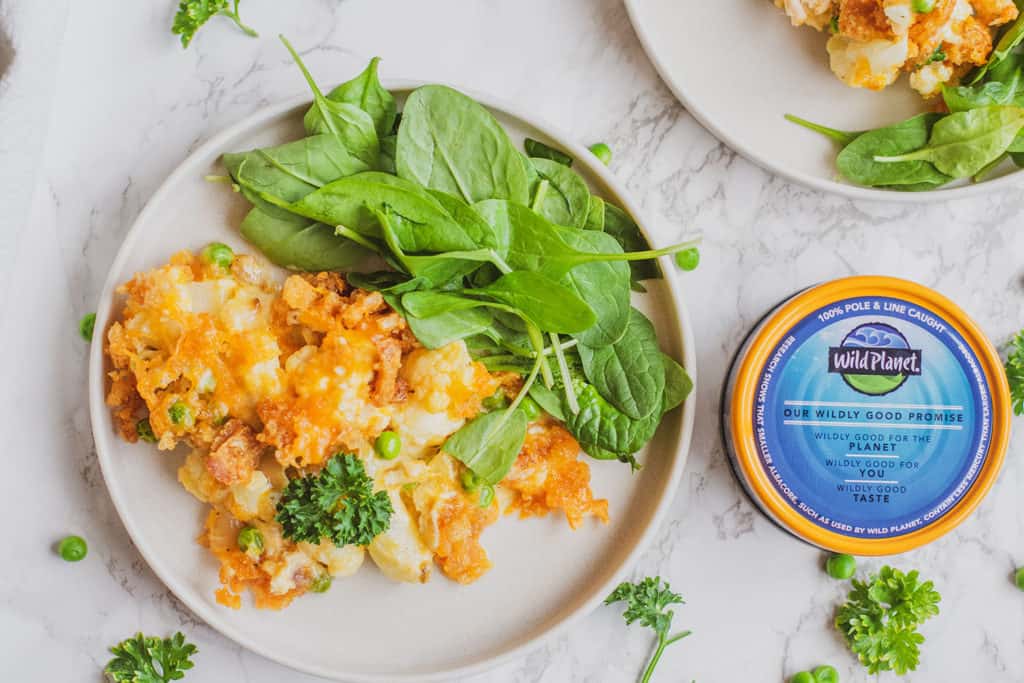 Keto tuna casserole on a white dish with spinach and parsley on the side and a can of wild planet foods tuna on the side.