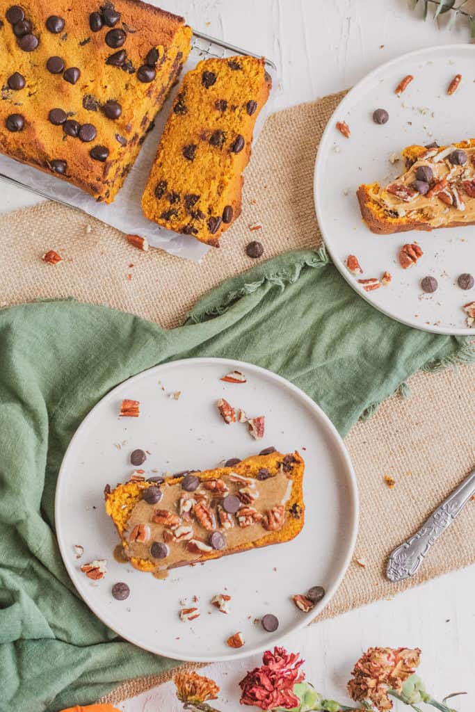 Keto Chocolate Chip Pumpkin Bread sliced on white plates with a green napkin on the side. 