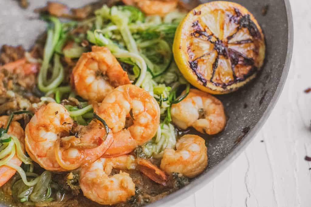Keto shrimp scampi with zucchini noodles, shrimp, and parsley is a grey skillet. 