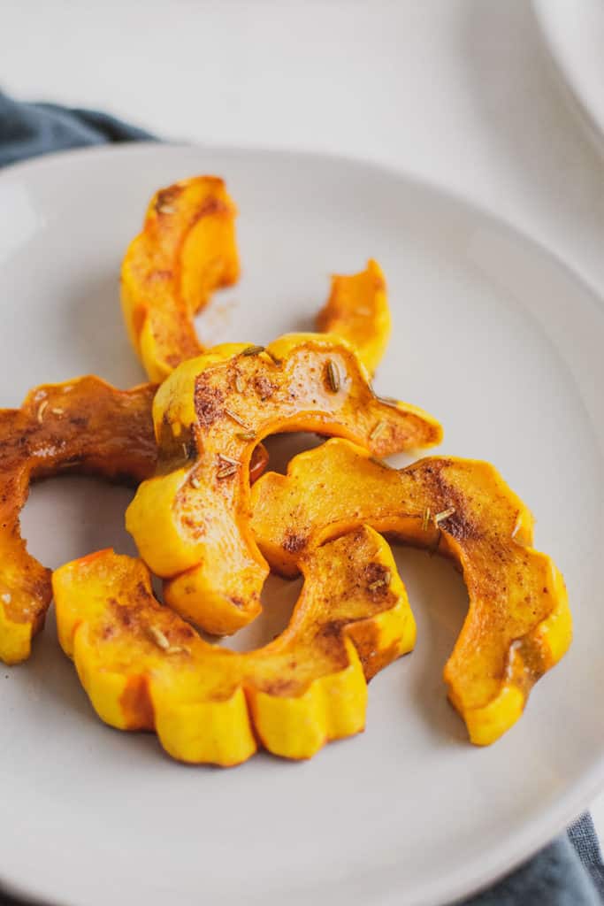 Keto roasted delicata squash on a white plate and surface.