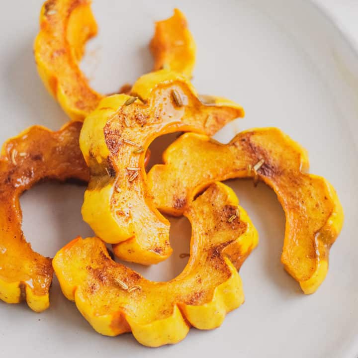 Keto roasted delicata squash on a white plate and surface.
