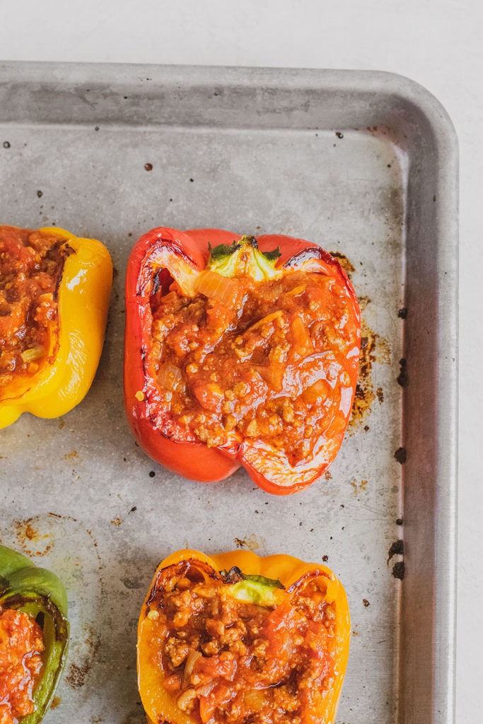 Keto Stuffed Bell Peppers with meat sauce and provolone cheese on top in a bell pepper on a silver tray