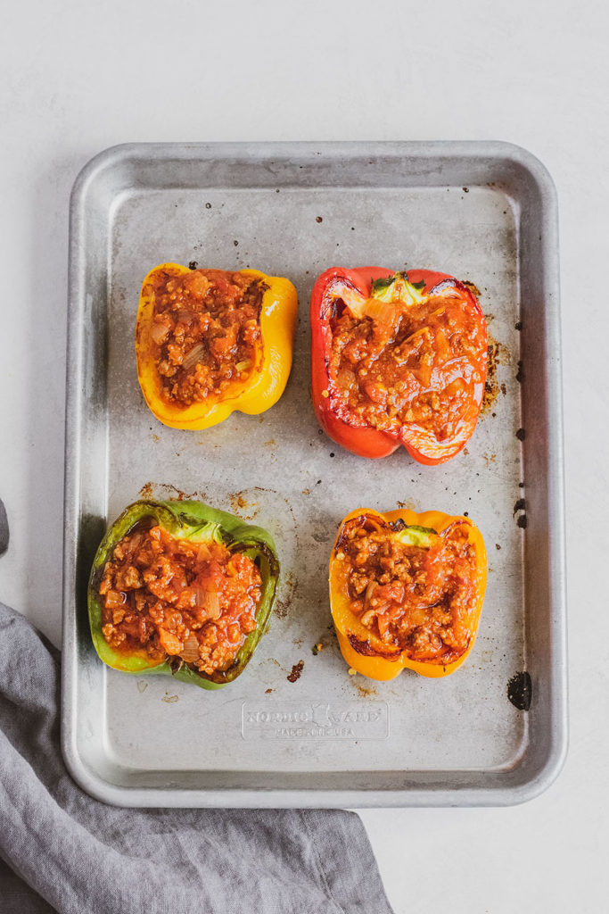 Keto Stuffed Bell Peppers with meat sauce and provolone cheese on top step on a silver tray